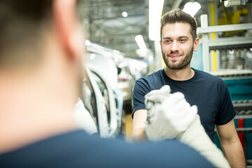 Two colleagues shaking hands in modern car factory
