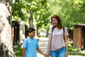 Naklejka premium Mother and son hold hands and smile at each other as they walk