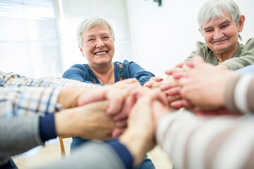 Group of active seniors stacking hands, symbolizing solidarity
