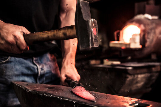 Knife maker at work, steel splinter during hammering damask steel - Powered by Adobe