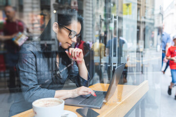 Business woman having a break in a cafe and working with a laptop