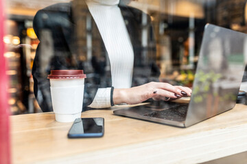 Close-up of businesswoman using laptop at a cafe in the city