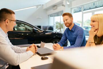 Salesperson advising couple in car dealership