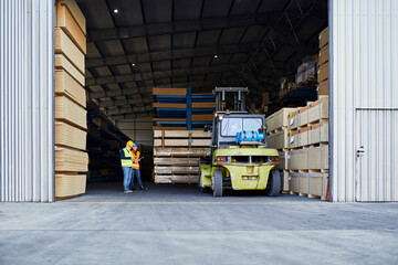 Two workers standing in factory warehouse next to forklift