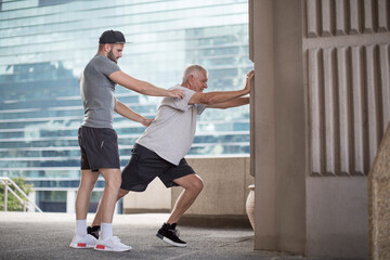 Fitness instructor guiding senior man doing a stretching exercise