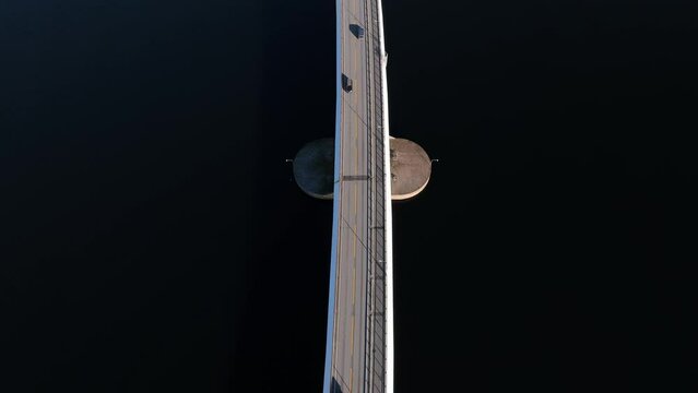 Top down aerial of traffic on Nordhordland Bridge, tilting up to reveal bridge tower and road towards Hordvik