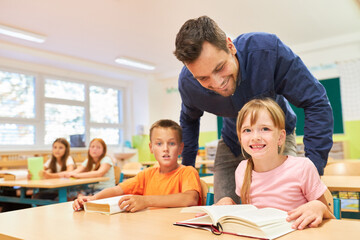 Teacher standing near students reading books