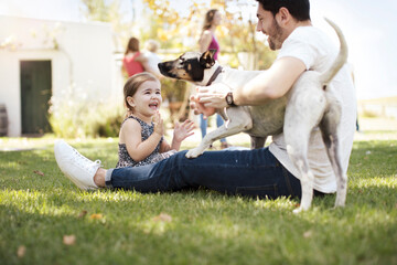 Happy father, daughter and dog in garden