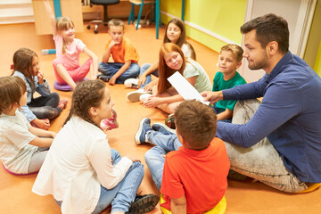 Teacher sitting on floor with students in class