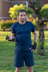 Fototapeta premium Focused Man Holding Dumbbell in Garden