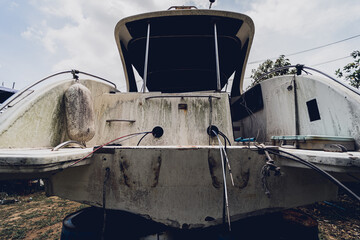 Old and rusty motor boats on a landfill surrounded by tropical forest