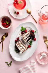 Pancake chocolate cake with fresh raspberries on a pink background.