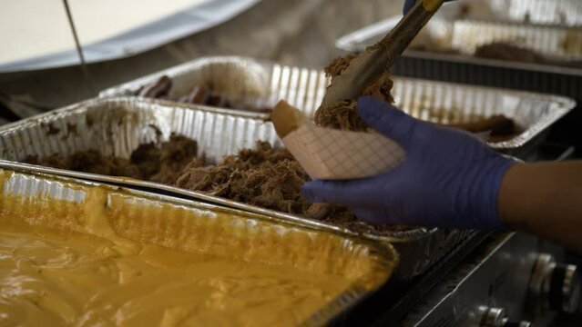 Delicious street food - pulled pork with cheese sauce placed on a paper tray.