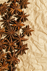 Brown Anise stars as pattern at sunlight, top view close up aromatic spices dried aniseed on beige paper, minimal aesthetic food, textured background, natural season traditional condiments