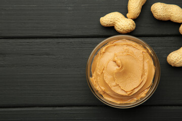 Bowl of peanut butter and peanuts on black background. Creamy peanut pasta in small bowl. Space for...