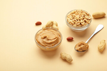 Bowl of peanut butter and peanuts on beige background. Creamy peanut pasta in small bowl.