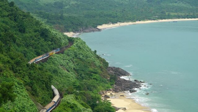 Top view of a passing train among the trees along the sea coastline