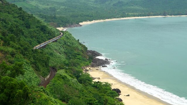 Top view of a passing train among the trees along the sea coastline