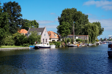 Obraz premium Scenic view of river by buildings against blue sky