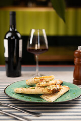 Turkish cheese lavash served on plate, red wine and glass on background. Luxurious Italian restaurant