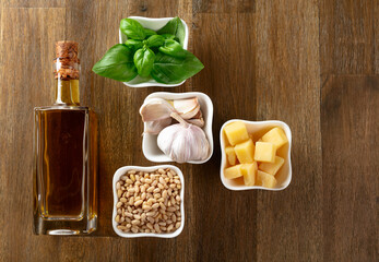 Ingredients for traditional Italian pesto recipe on a wooden background.
