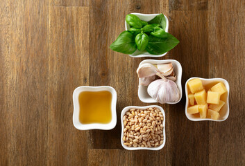 Ingredients for traditional Italian pesto recipe on a wooden background.