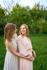 two women hug and pose against the background of nature