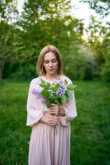 a portrait of a beautiful young woman with a bouquet of lilacs