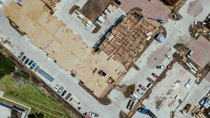 Straight aerial view multistory apartment complex under construction timber wood frame, elevator vertical shaft, large courtyard, slab foundation, worker heavy equipment, downtown Dallas, Texas