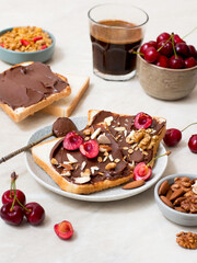 Toasts spread with chocolate spread with berries, cherries, nuts and coffee.