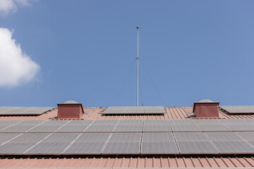 A roof with  dirty solar panels on it and a pole in the middle