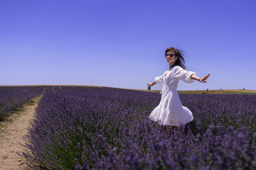 Woman in white dress dance in blooming fragrant lavender on fields. Bushes of lavender purple...