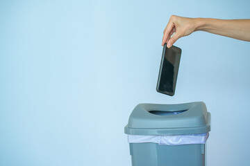 Female putting smartphone in a trash bin, concept of digital detox