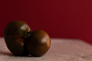 Tomate kumato sobre mesa blanca con fondo rojo
