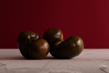 Tomate kumato sobre mesa blanca con fondo rojo