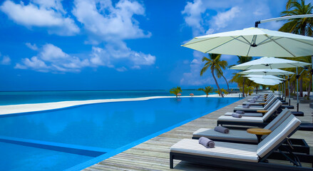 Fototapeta premium Bedchair near poolside in the tropical blue background