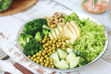 A bowl with a salad made of green vegetables	