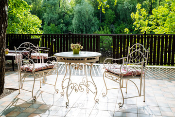 A table and chairs on a patio with trees in the background