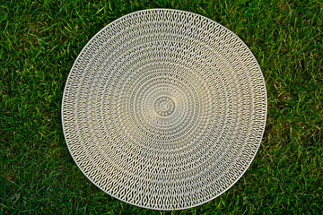 Fototapeta premium ażurowy wzór, złota podkładka na stół na tle trawnika, wzór mandala, gold table mat, mandala pattern, Decorative Doily, Gold table mat surface as background, closeup 