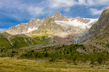 Obraz premium Tour du Montblanc beautiful mountain ladscapes of the Alps green valley, snow summit of Montblanc and rocky peaks of Aiguille du Midi in summer sunny weather blue sky, trekking and hiking in Chamonix