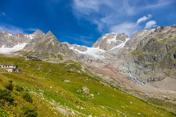 Tour du Montblanc beautiful mountain ladscapes of the Alps green valley, snow summit of Montblanc and rocky peaks of Aiguille du Midi in summer sunny weather blue sky, trekking and hiking in Chamonix