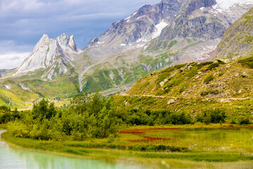 Obraz premium Tour du Montblanc beautiful mountain ladscapes of the Alps green valley, snow summit of Montblanc and rocky peaks of Aiguille du Midi in summer sunny weather blue sky, trekking and hiking in Chamonix