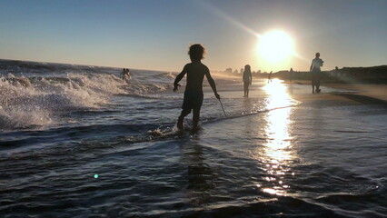 Fototapeta premium Little boy at the beach playing, silhouette