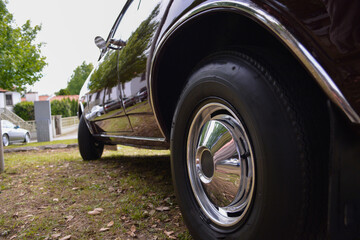 A luxury car in retro style is waiting for its owner on the grass in front of the house.
