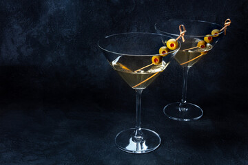 Martini. Two glasses of dirty martini cocktails with vermouth and olives, aperitif, on a black background, with a place for text