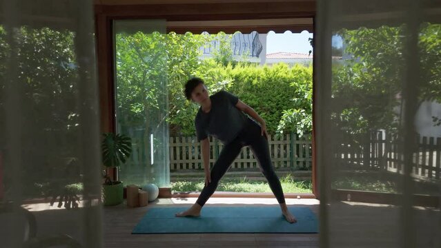 Woman doing yoga on a fitness mat in the balcony, triangle pose