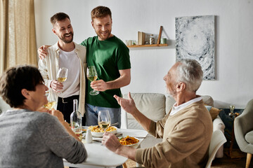 A gay couple toasts with parents during a dinner at home.