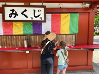 A mother and daughter getting their omikuji, or written fortunes, as the Senso-ji Temple or Asakusa Kannon Temple in Tokyo, Japan