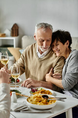 Mature parents share meal with their son and his partner at a cozy dinner at home.
