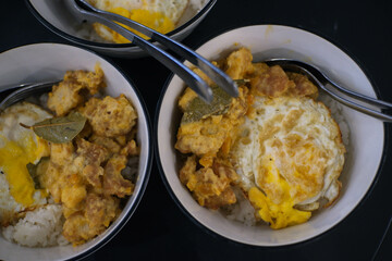 Rice with egg, flour chicken and lime leaf peel in a white bowl